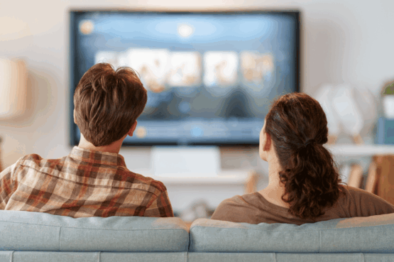 Un homme et une femme assis dans un canapé et qui regarde la TV