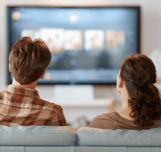 Un homme et une femme assis dans un canapé et qui regarde la TV