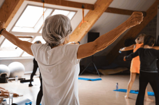 Femme senior active pratiquant une séance de fitness doux et de bien-être dans une salle chaleureuse de Kineo, un exercice recommandé pour le cœur et la santé.
