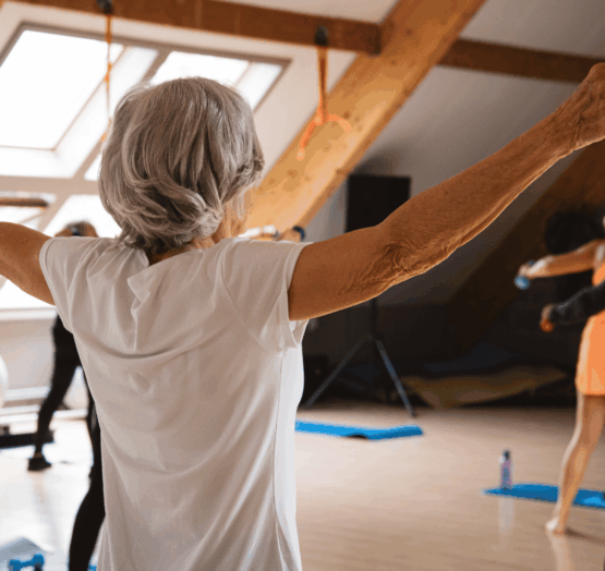 Femme senior active pratiquant une séance de fitness doux et de bien-être dans une salle chaleureuse de Kineo, un exercice recommandé pour le cœur et la santé.