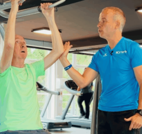 Un coach Kineo accompagne un membre sur un exercice de renforcement après une rééducation